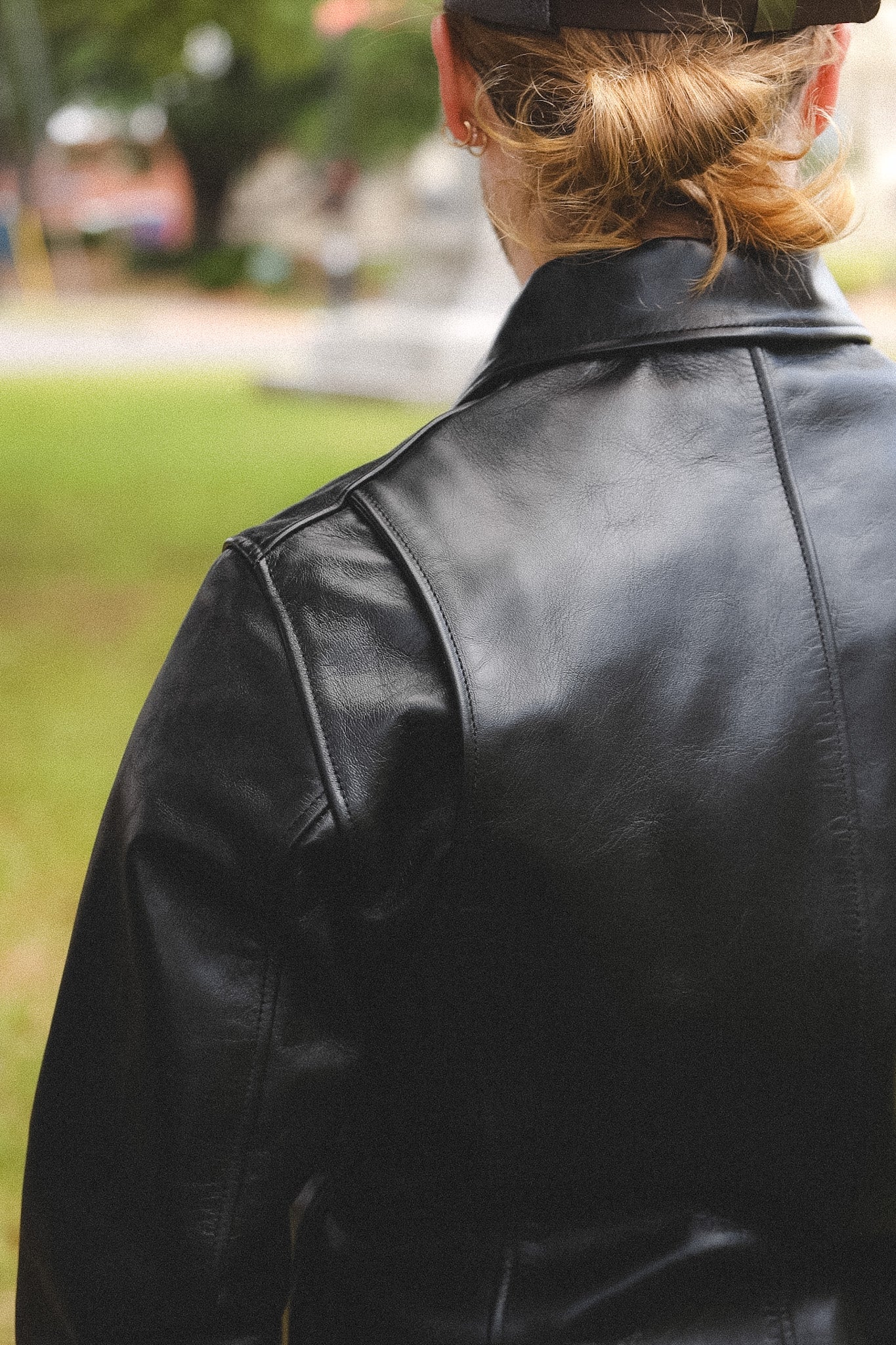 A person wearing a black horsehide rider's jacket with a collar, standing outdoors.