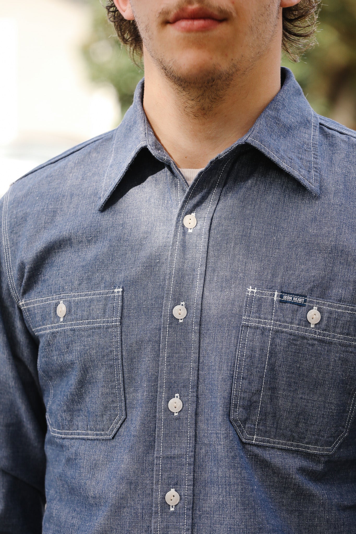 Close-up of a person wearing a blue denim shirt with a blurred background