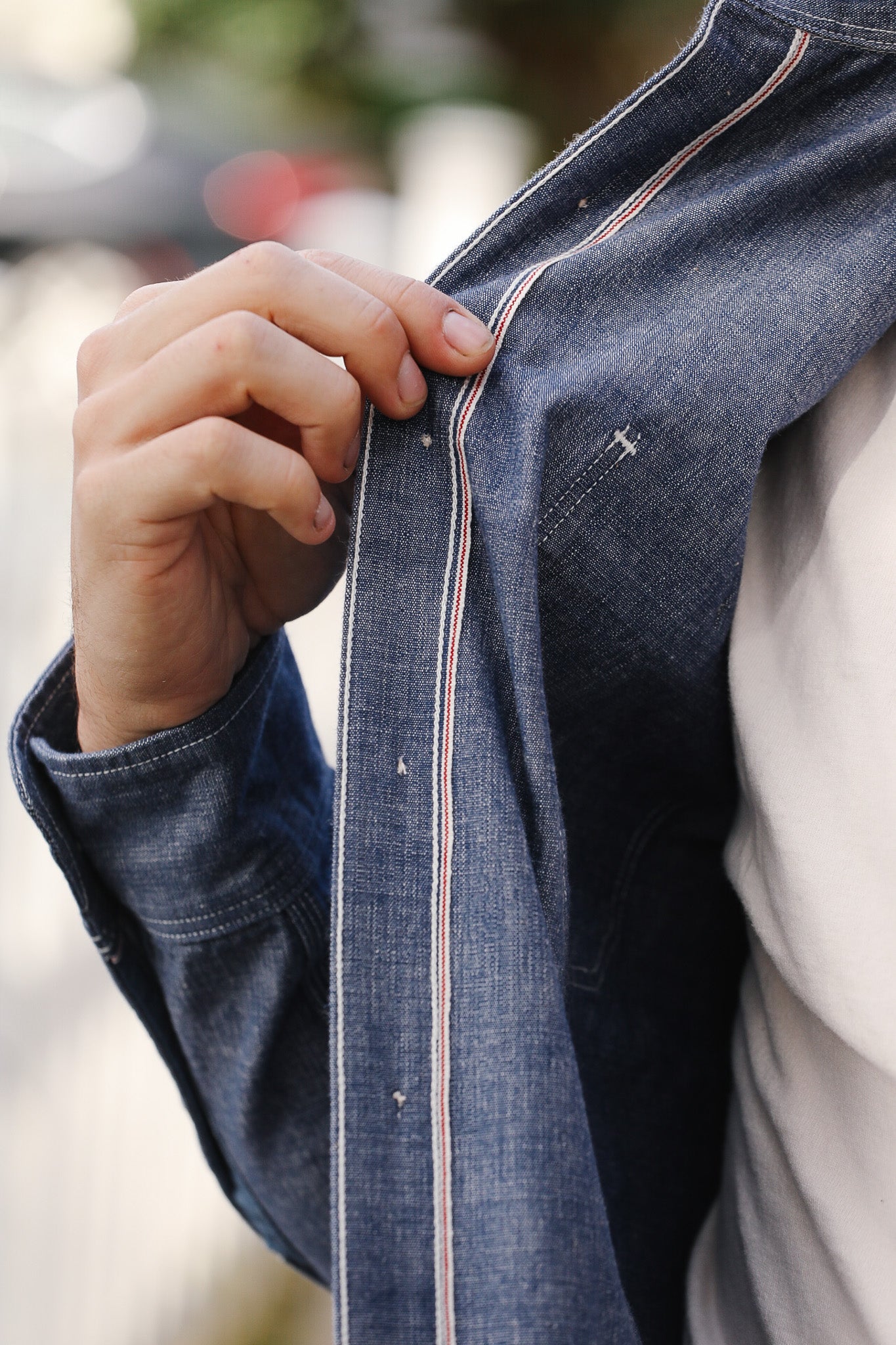 Person adjusting a zipper on a denim jacket with a blurred background
