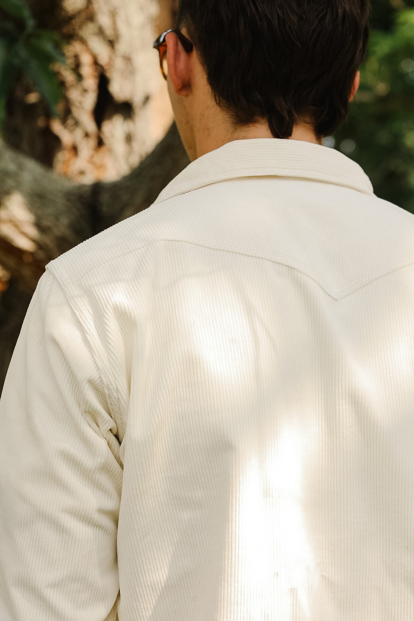 Person wearing a light-colored jacket with a blurred natural background