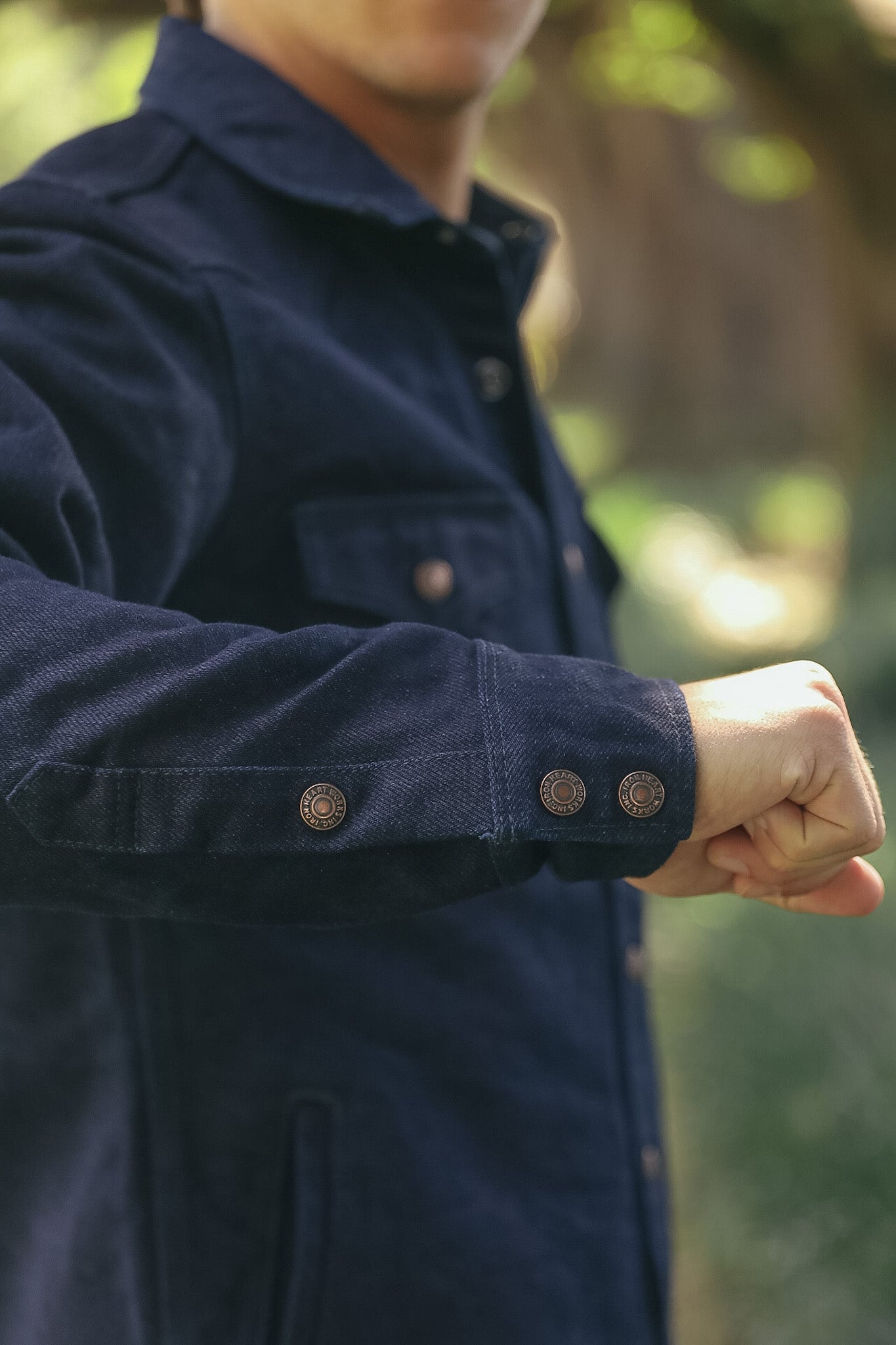 Close-up of a person wearing a dark navy blue corduroy jacket outdoors, showing the textured fabric and buttoned cuffs.