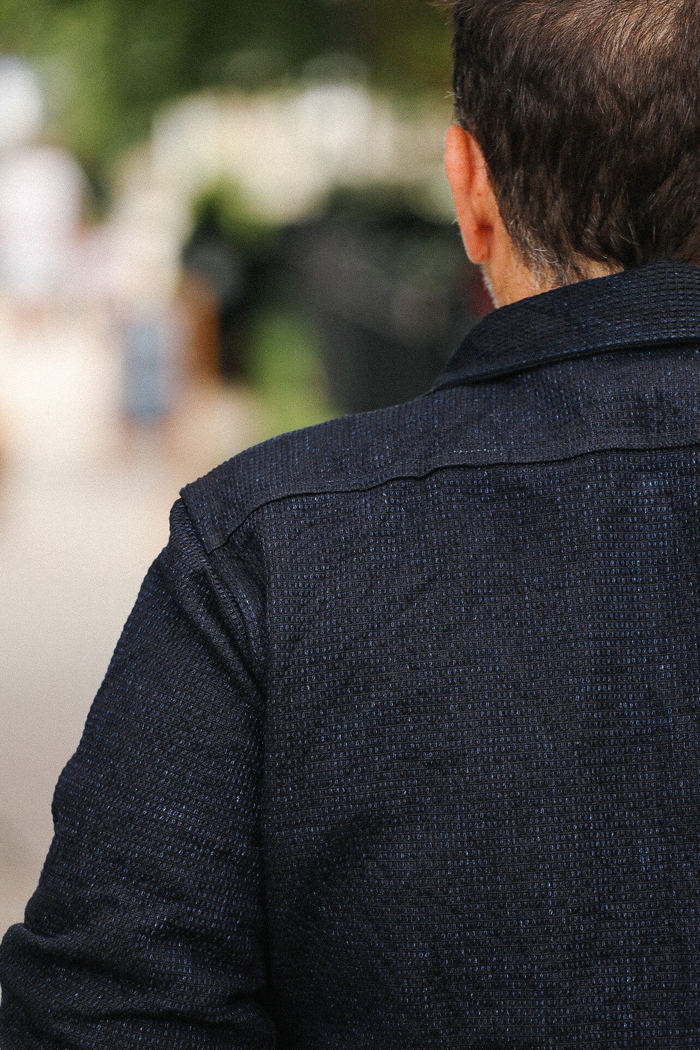 Person wearing a dark jacket with a blurred outdoor background