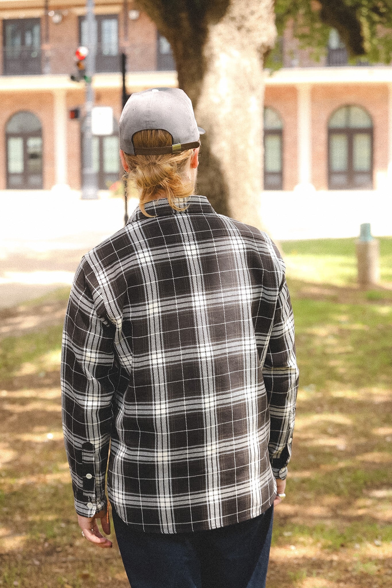 man wearing plaid black shirt standing outdoors on a blurred background 