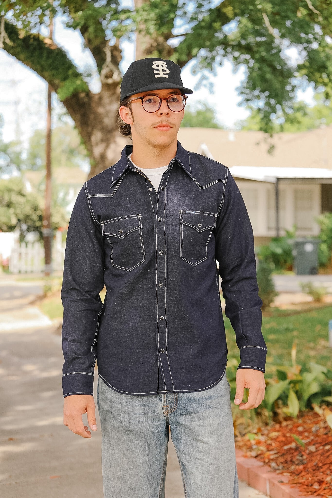 Man wearing a dark denim shirt and cap outdoors