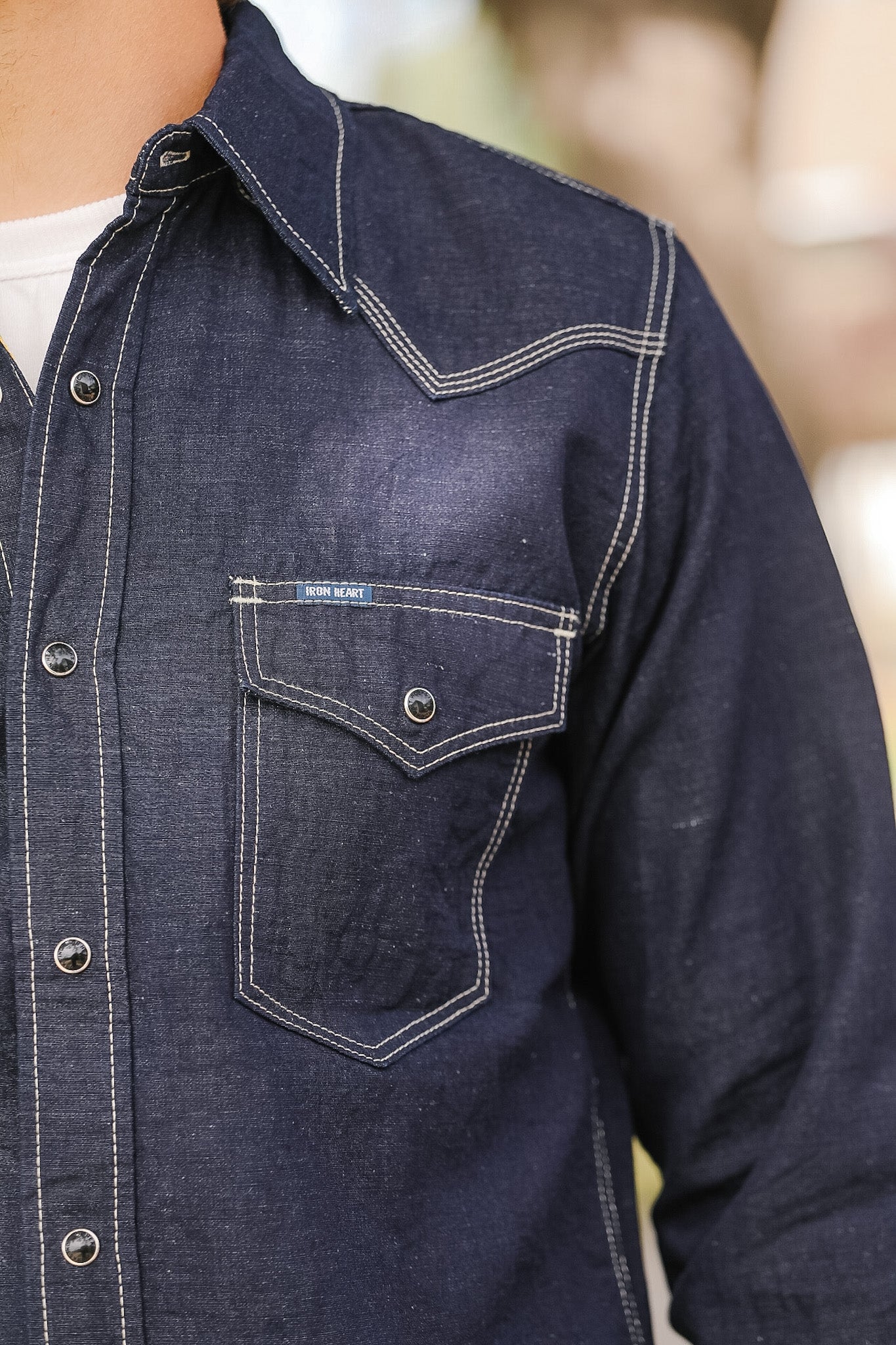 Close-up of a dark denim shirt with a pocket detail.