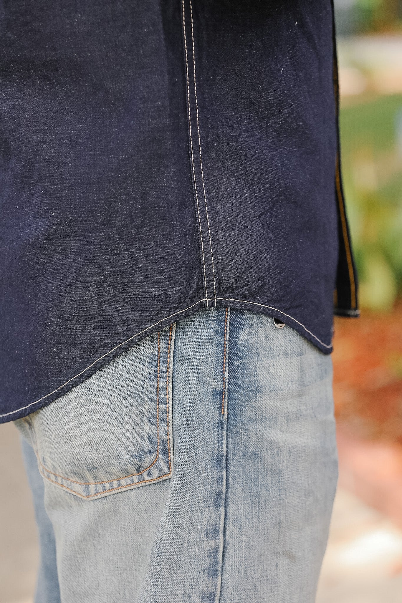 Close-up of a person wearing a dark blue denim jacket and light blue jeans.