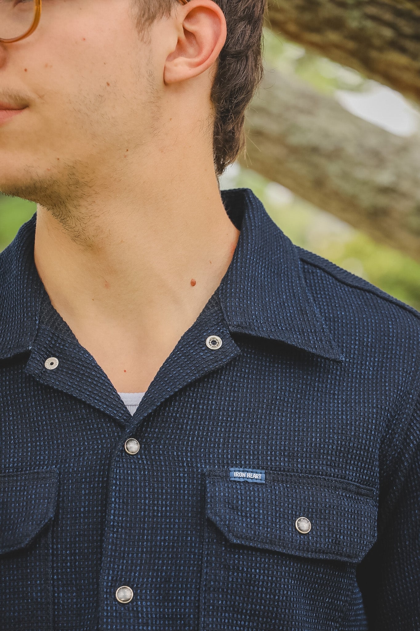 Close-up of a person wearing a navy blue textured shirt with a brand label.
