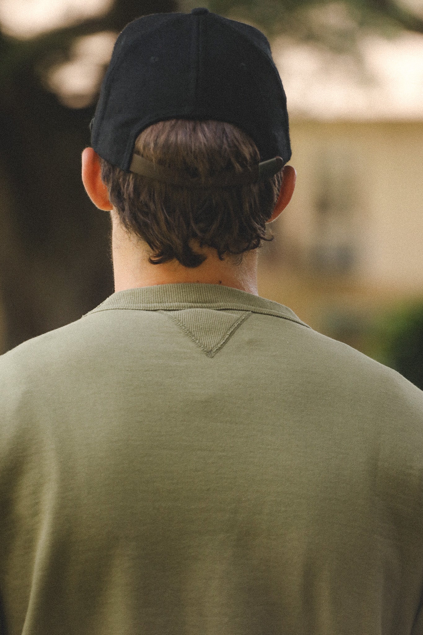 Person wearing a black cap and green shirt with a blurred background