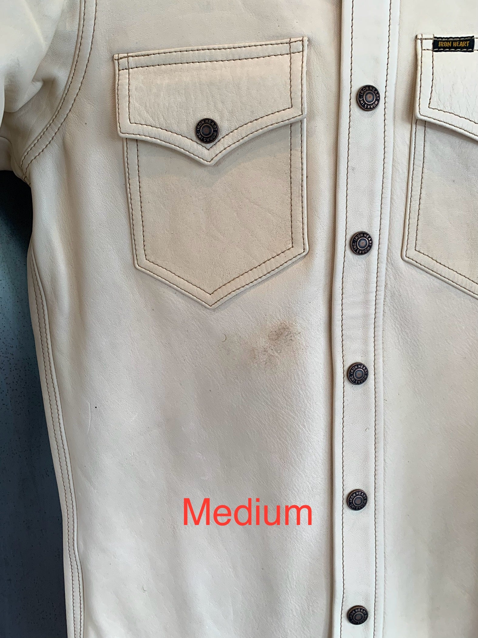 Close-up of medium off-white Iron Heart leather jacket with detailed pockets and branded snap buttons
