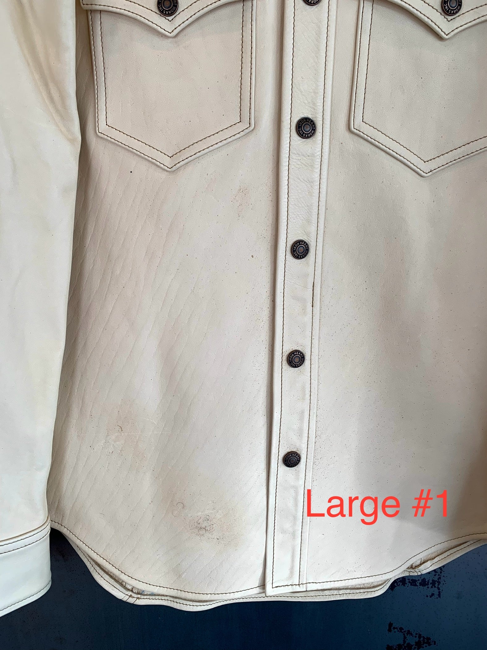 Close-up of cream leather western shirt with snap buttons and chest pockets, showing texture and stitching
