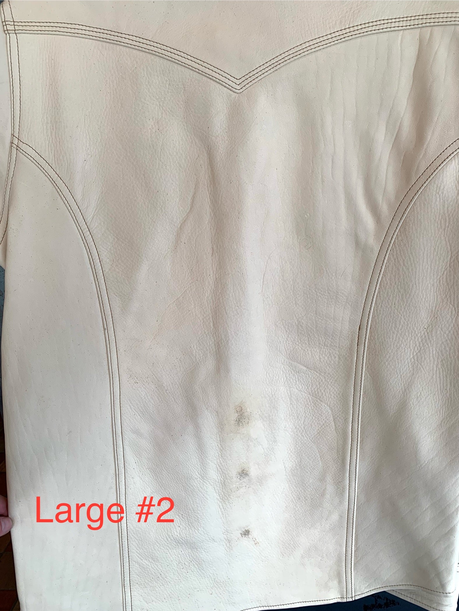 Close-up of large white leather panel with visible stitching and minor dirt marks, labeled Large 