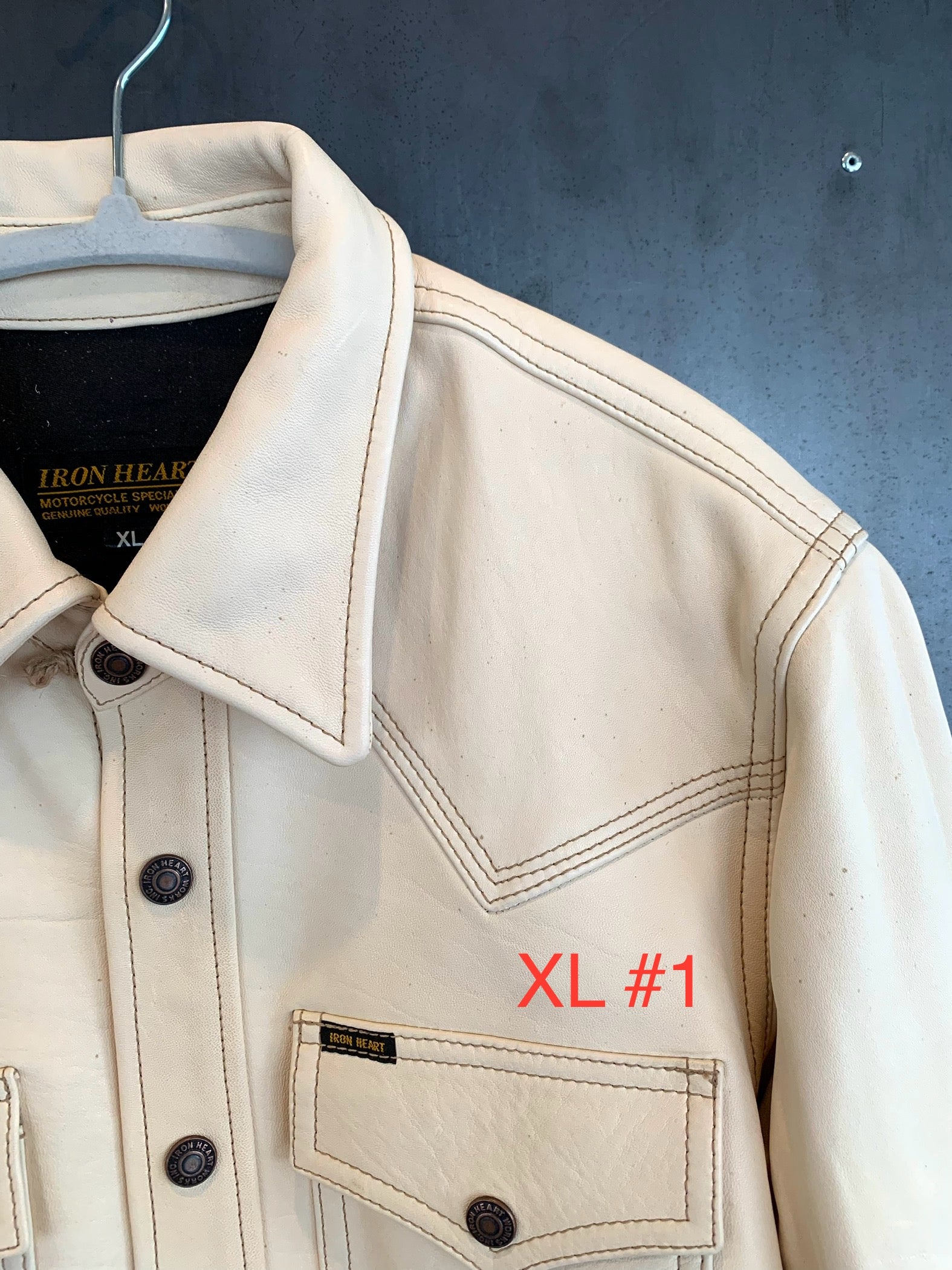 Close-up of cream leather Iron Heart motorcycle jacket with detailed stitching and branded buttons