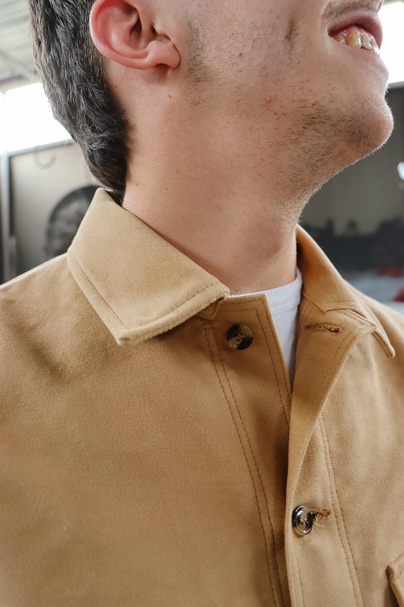 Close-up of a person wearing a beige jacket with a blurred background
