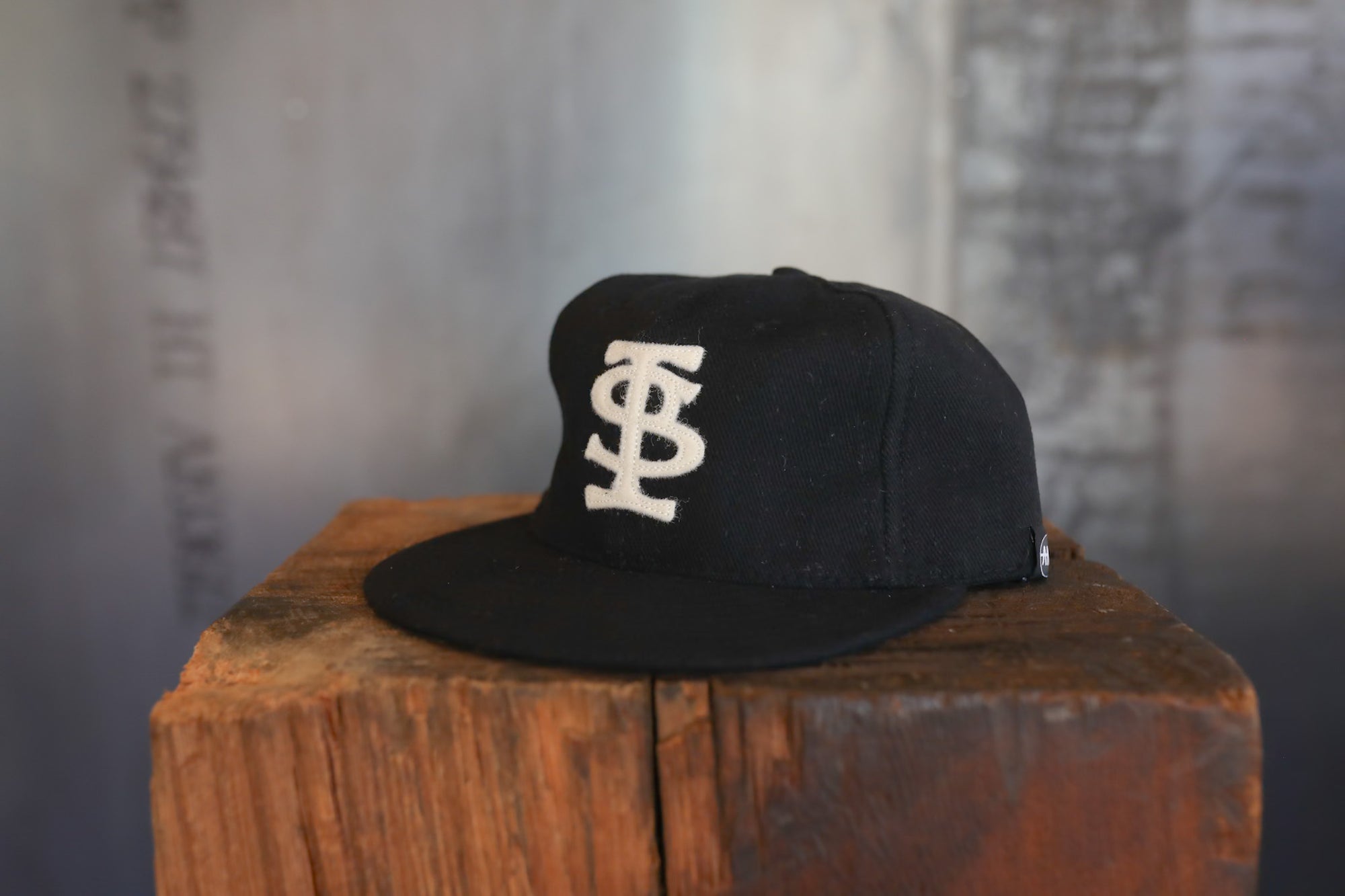Black cap with a white logo on a wooden block against a blurred background