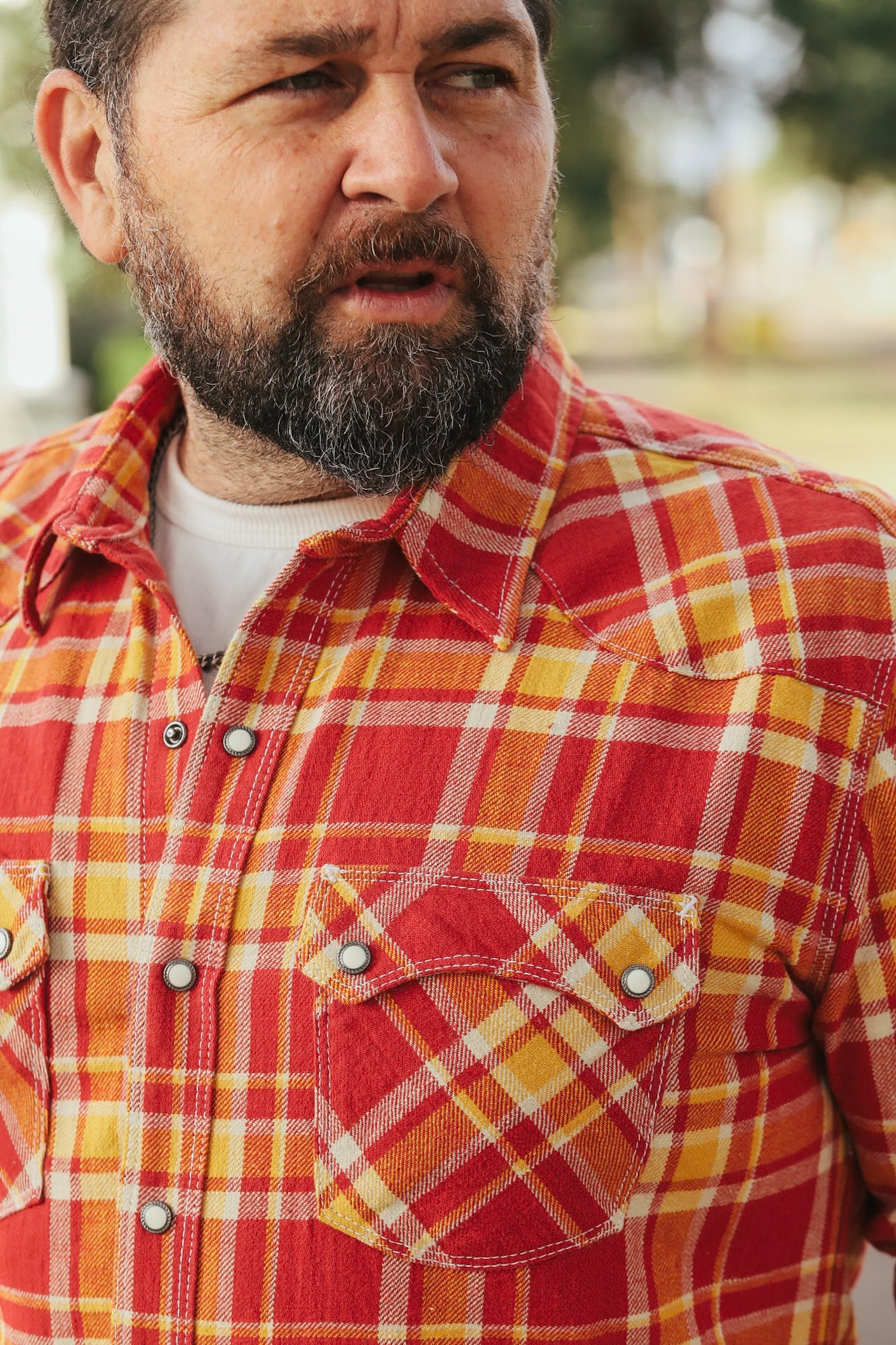 Man wearing a red and yellow plaid shirt outdoors