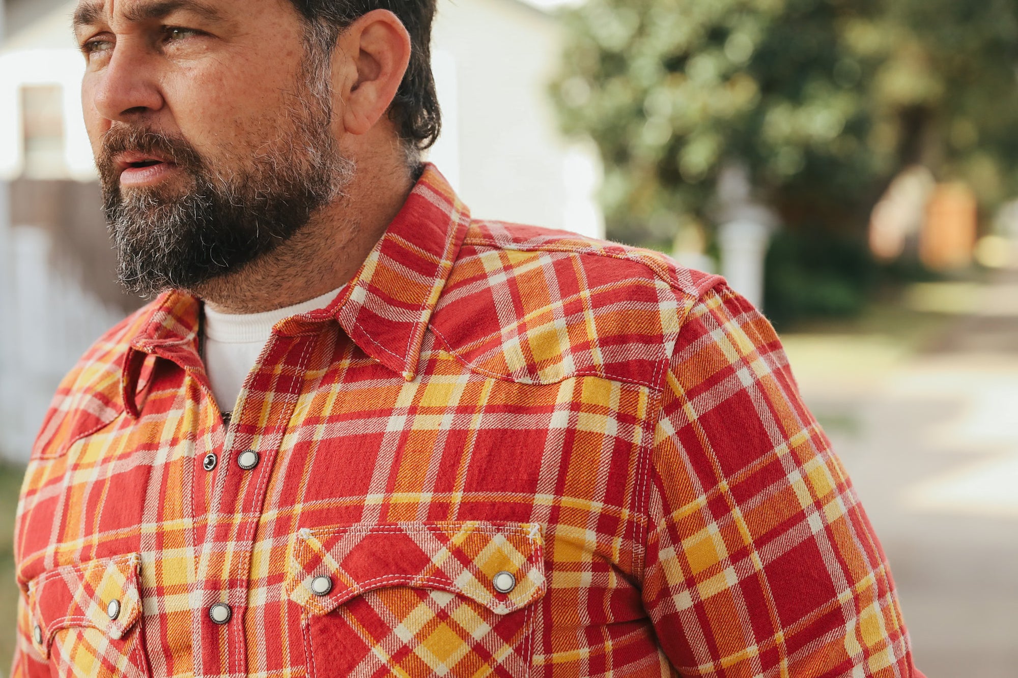 Man wearing a red and yellow plaid shirt outdoors