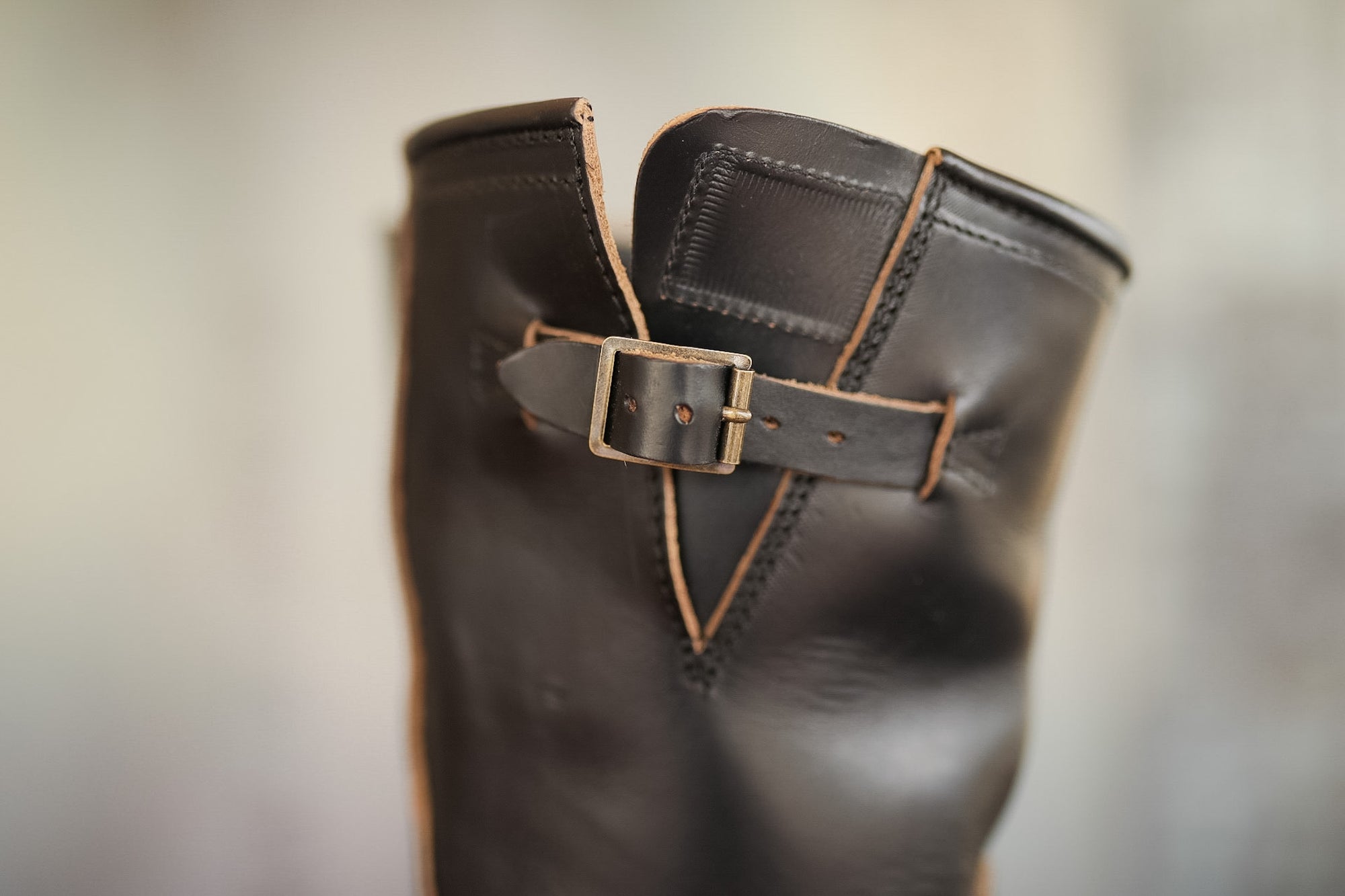 Close-up of a dark brown leather boot with a buckle on a blurred background