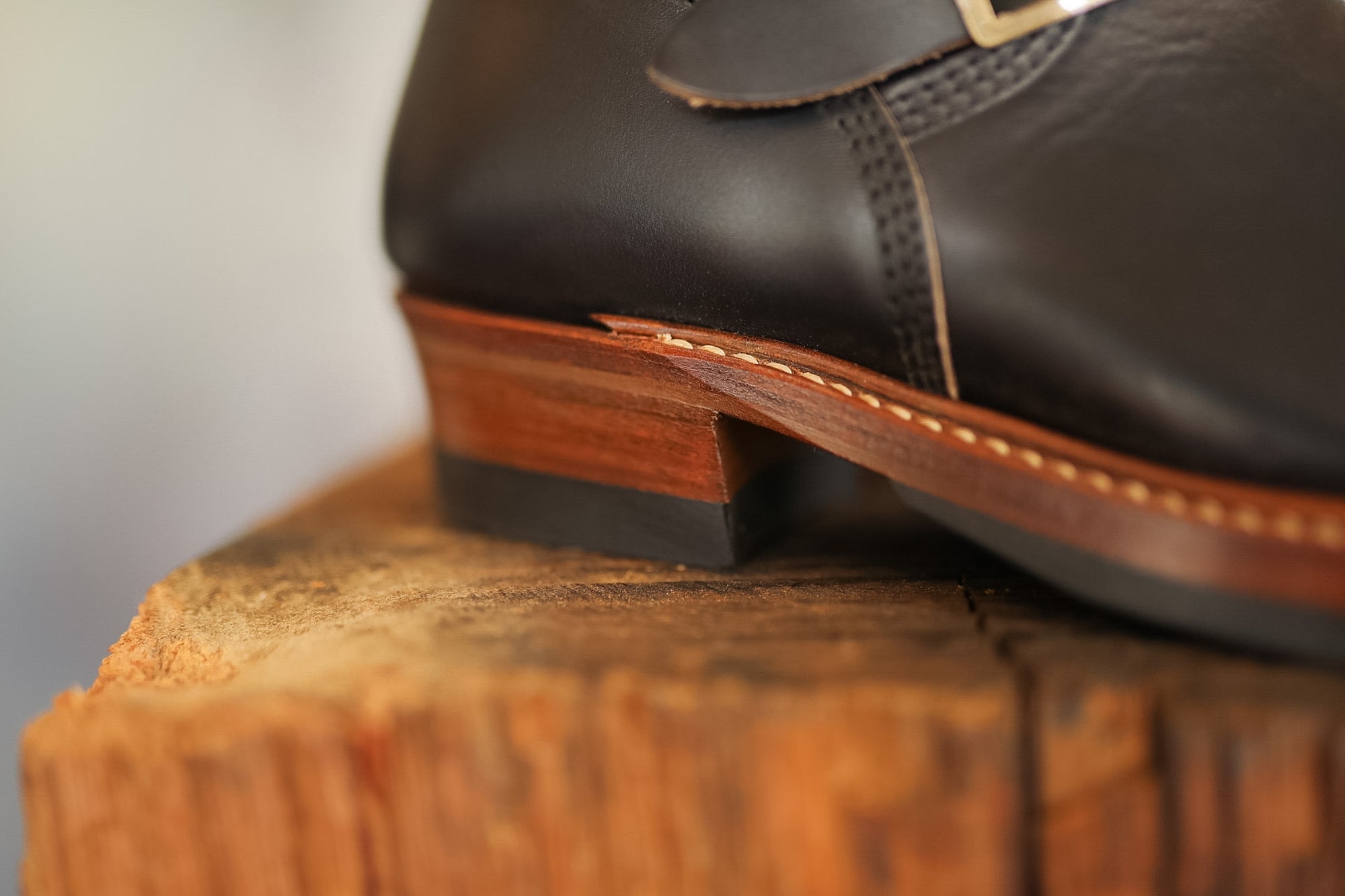 Brown leather shoe on a wooden block with a blurred background