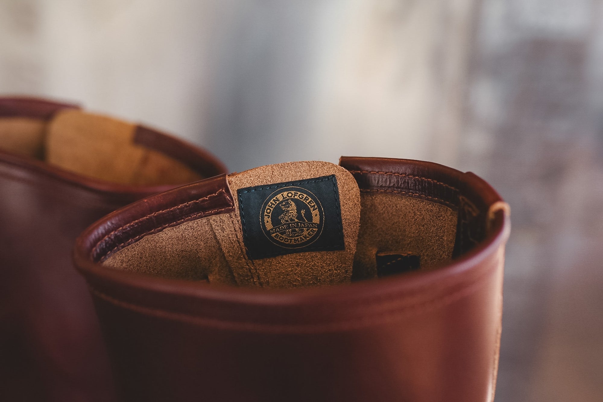 Close-up of a brown leather boot interior showing a tan footbed and a dark navy brand patch with a gold eagle logo.