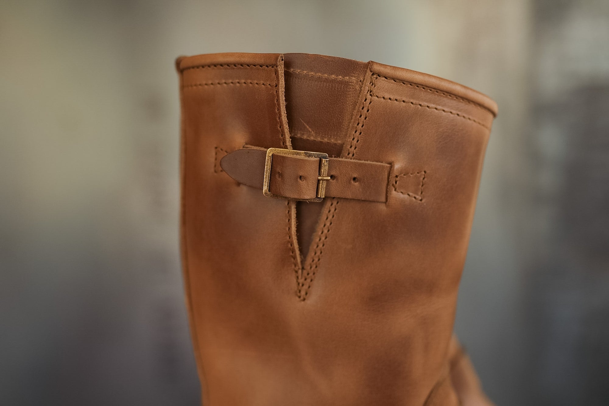 Brown leather boot with a buckle on a blurred background