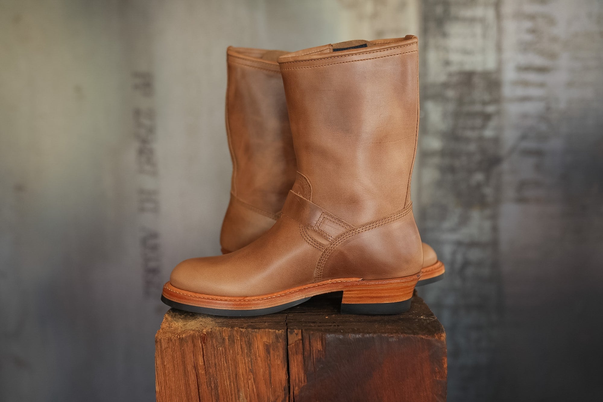 Pair of brown leather boots on a wooden block with a textured background