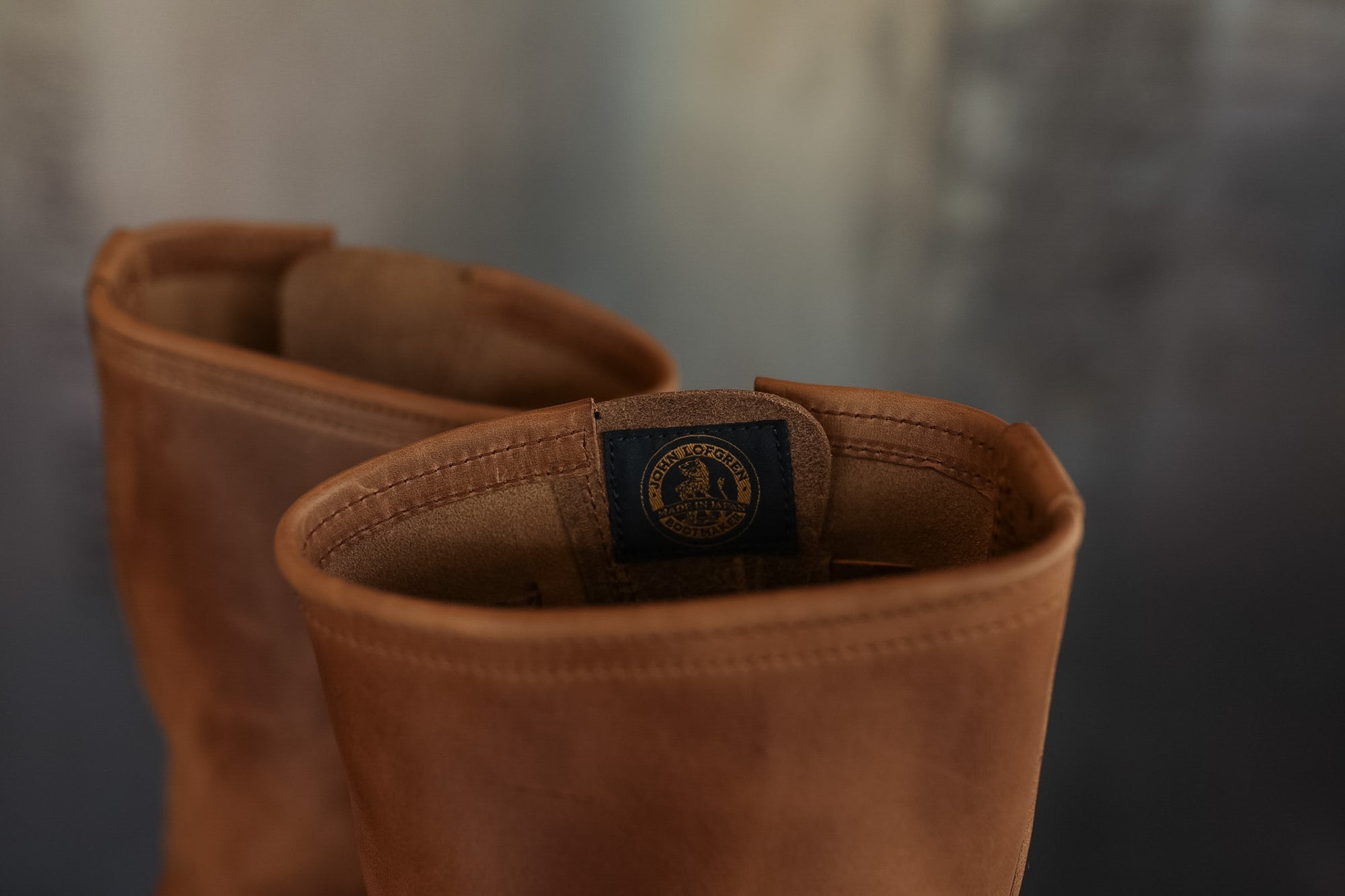 Pair of brown leather boots with a brand logo on a blurred background