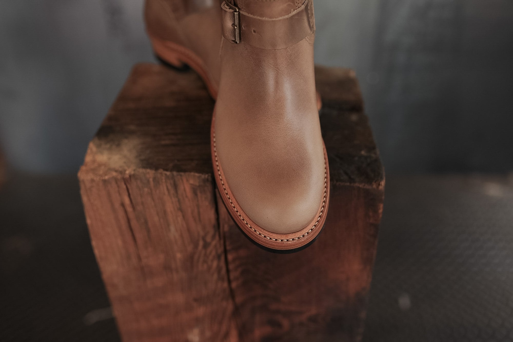 Brown leather boot on a wooden block with a blurred background