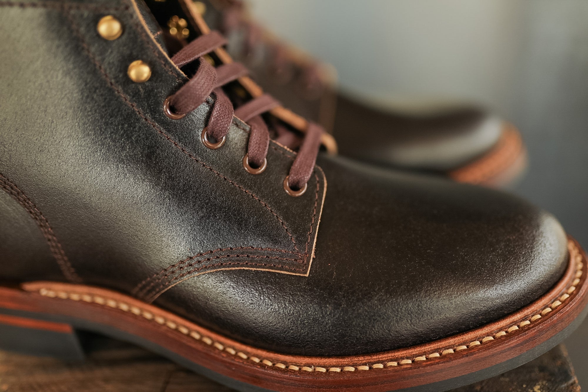 Close-up of brown leather boots with gold buttons on a blurred background