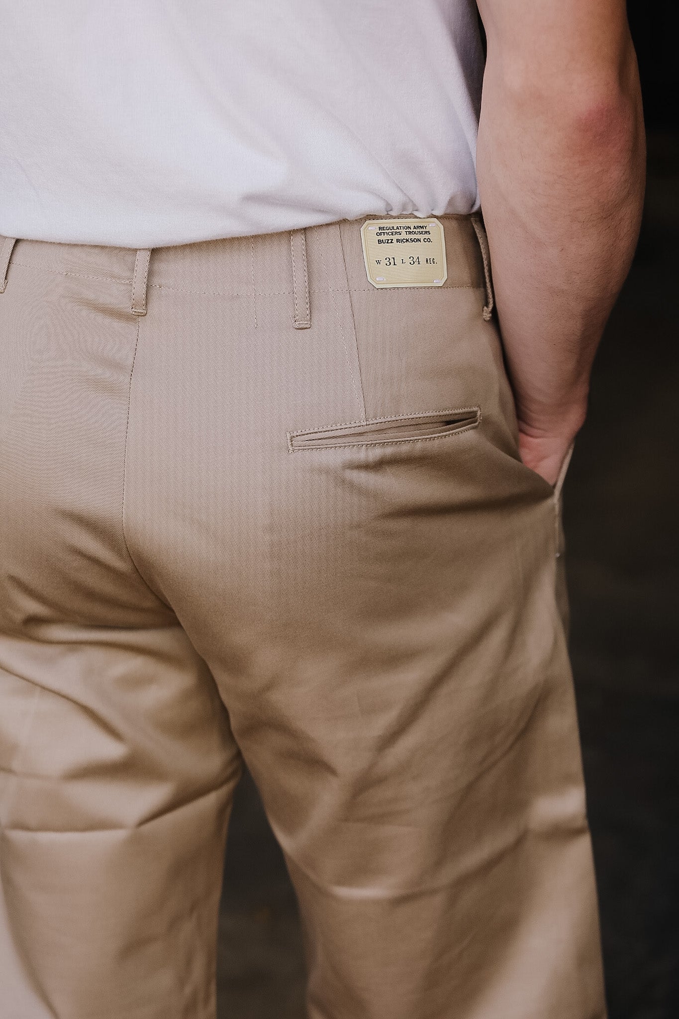 Beige pants with a visible brand tag on a dark background