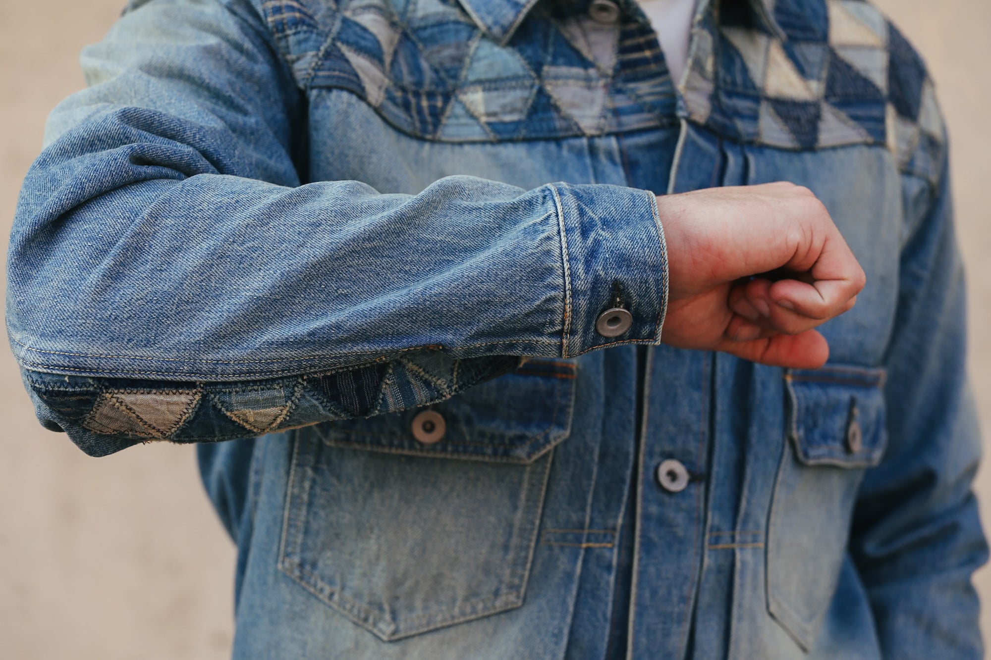 Close-up of a person wearing a blue denim jacket with rolled-up sleeves.