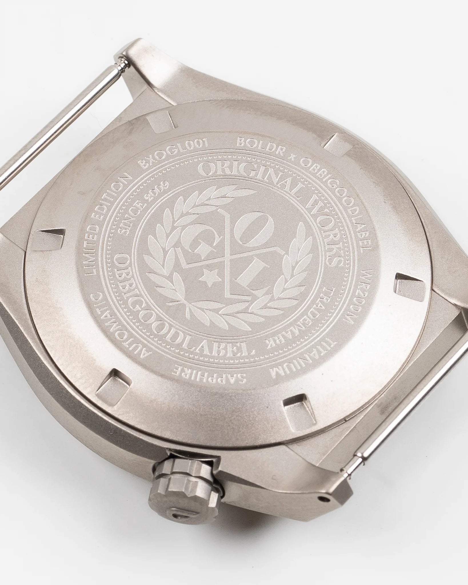 Close-up of the titanium watch back case with engravings including BOLDR x OBLIGOODLABEL, sapphire, automatic, and 200M water resistance
