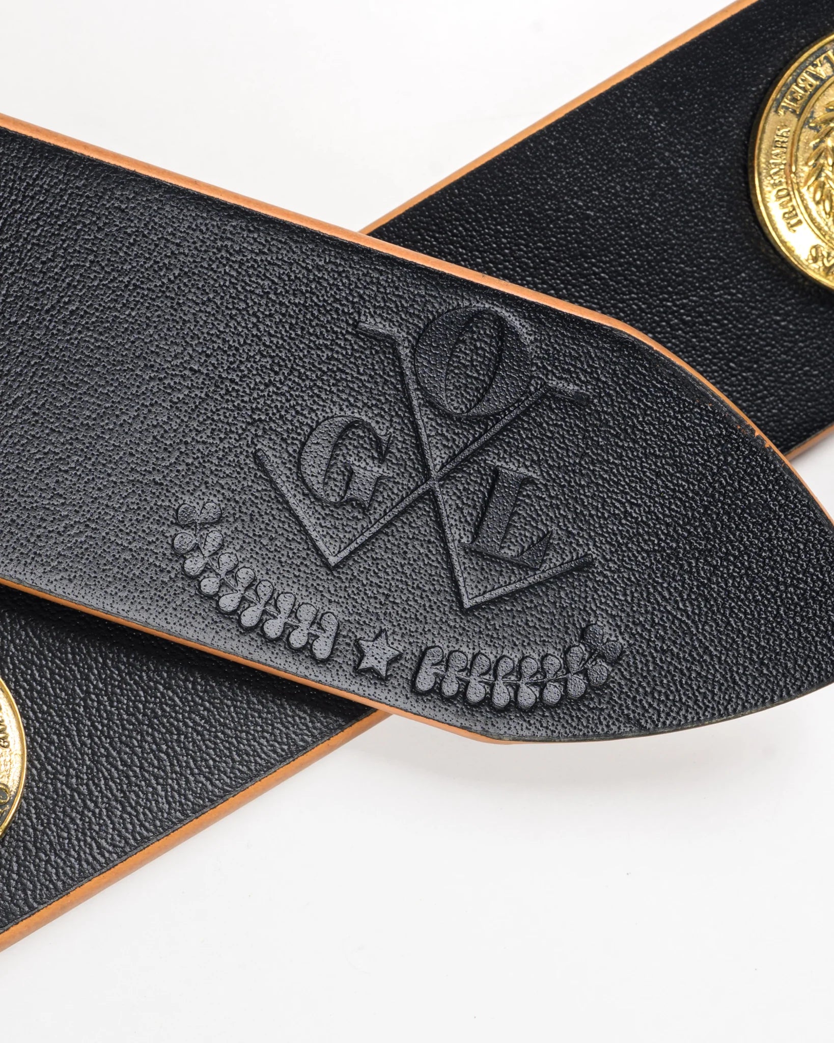 Black leather strap with gold buttons and embossed logo on a white background