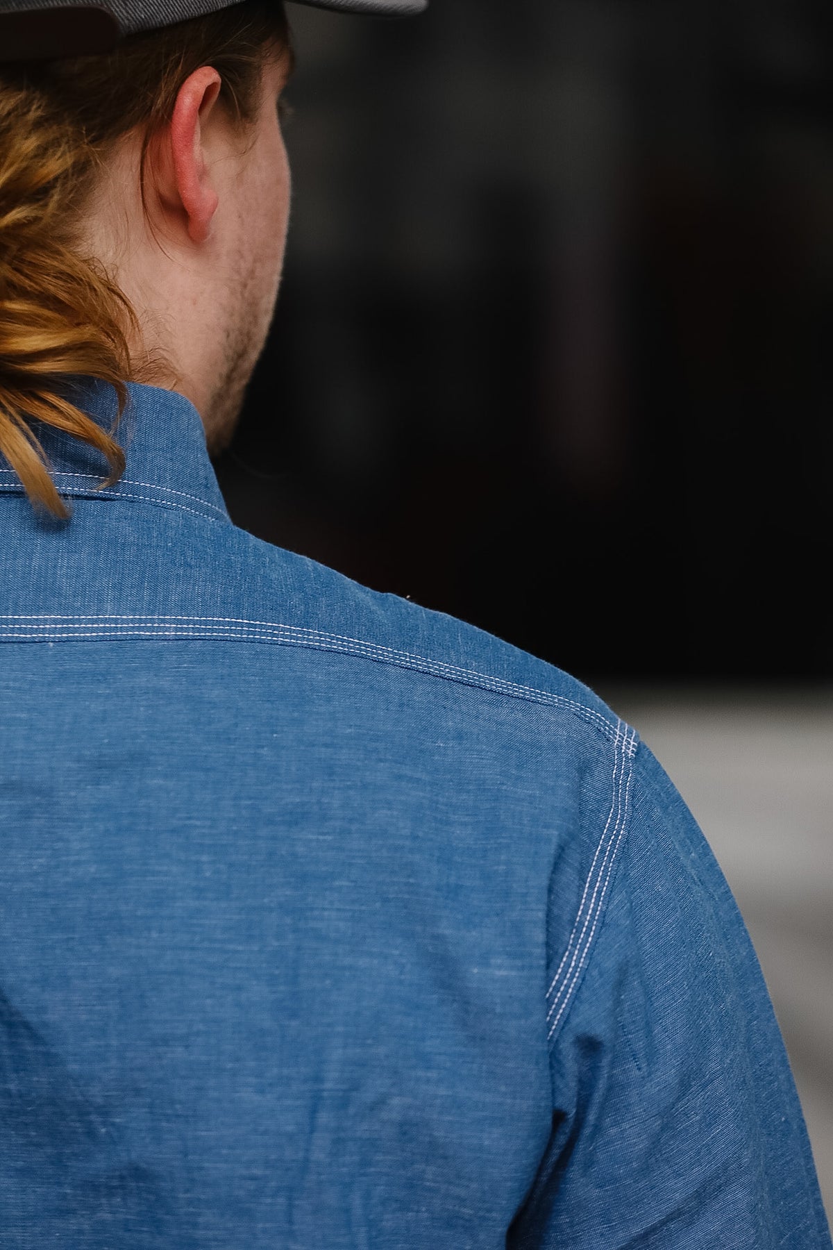 Person wearing a blue denim shirt with a blurred background