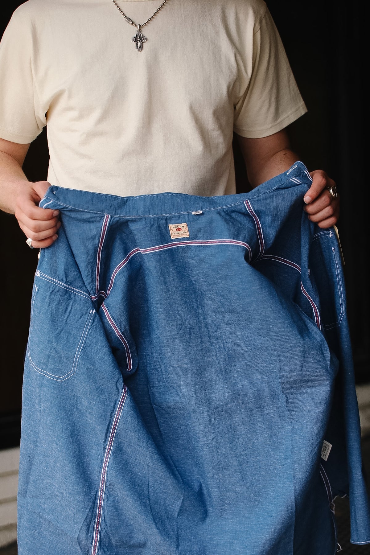 Person holding a pair of blue denim pants with a dark background