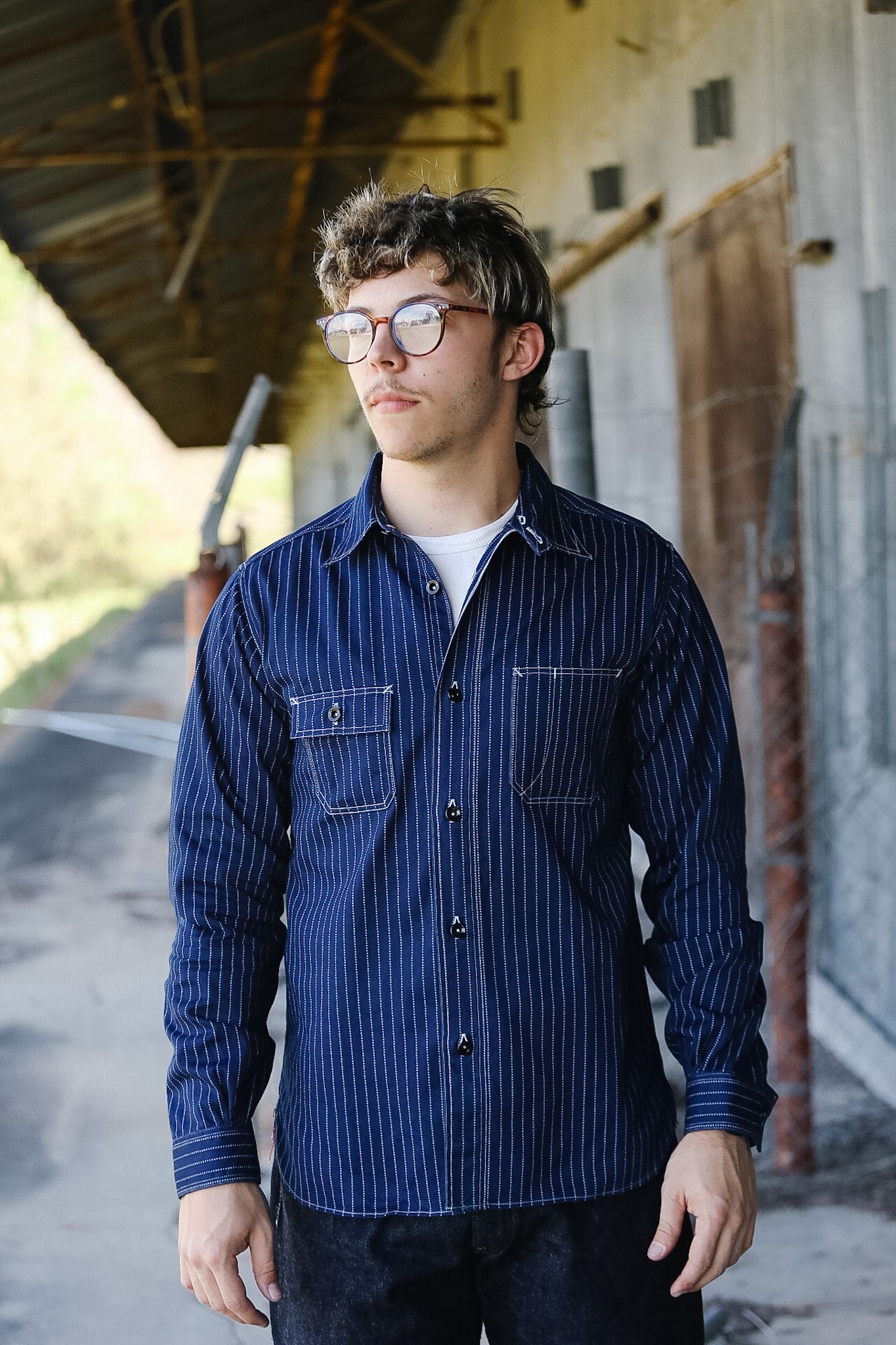 Person wearing a blue striped shirt standing in an industrial setting
