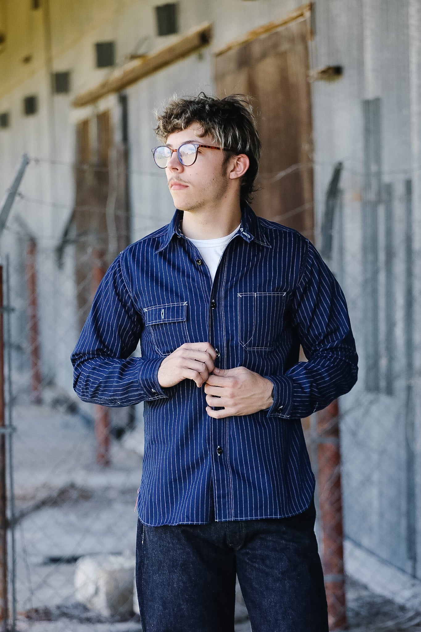 Man wearing a blue striped shirt standing in an industrial setting