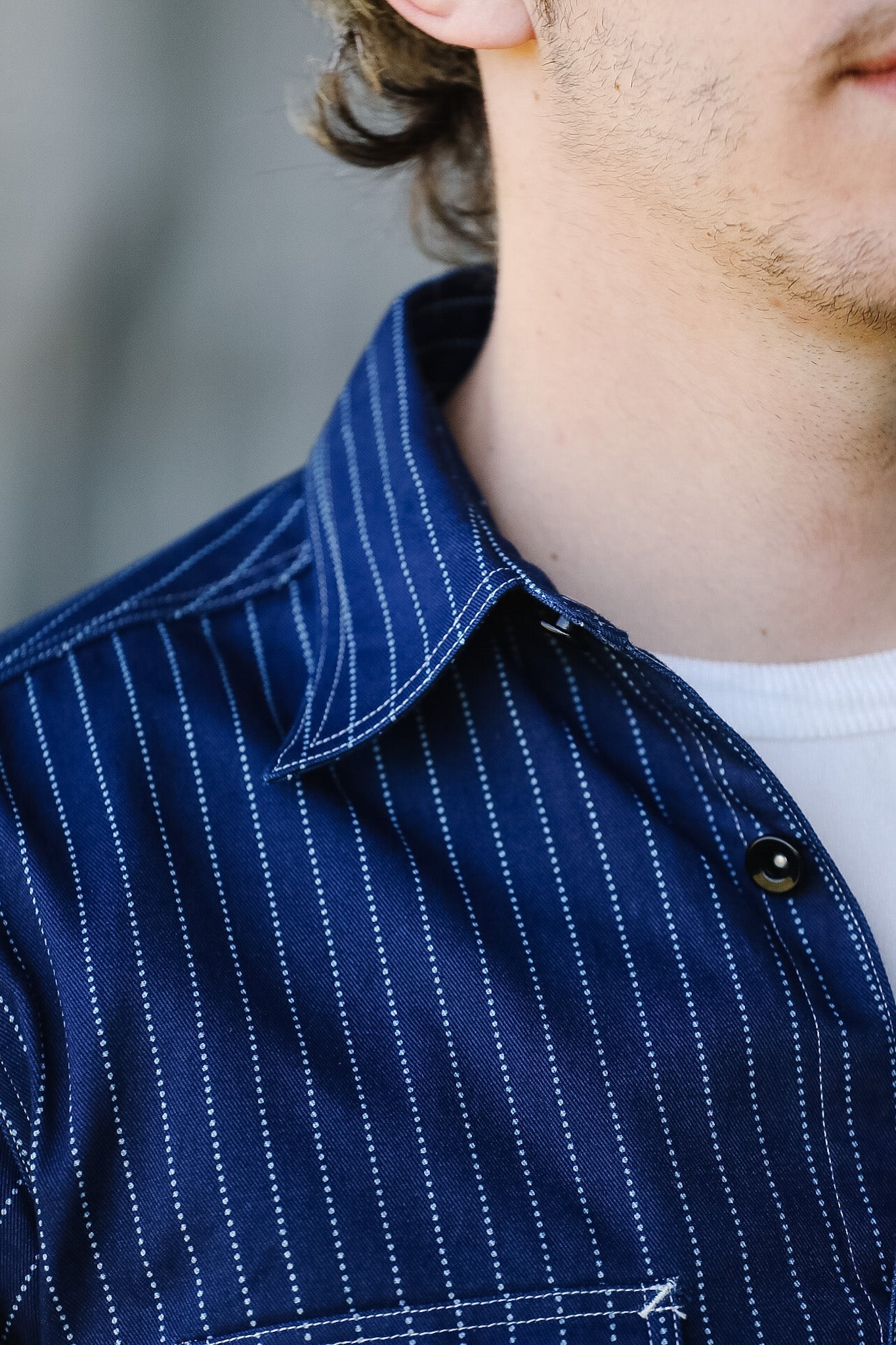 Close-up of a person wearing a blue pinstripe shirt with a blurred background