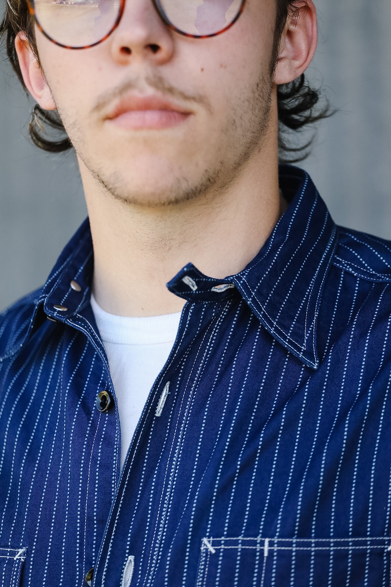 Close-up of a person wearing a blue striped shirt with a neutral background