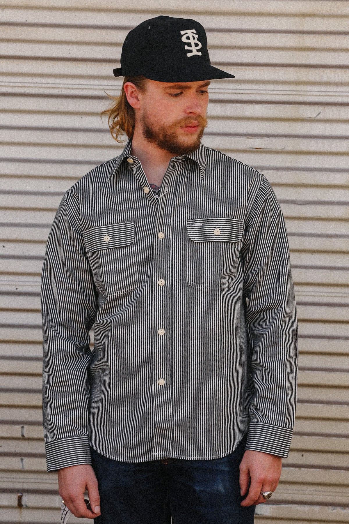 man wearing striped denim shirt on a metal backdrop 