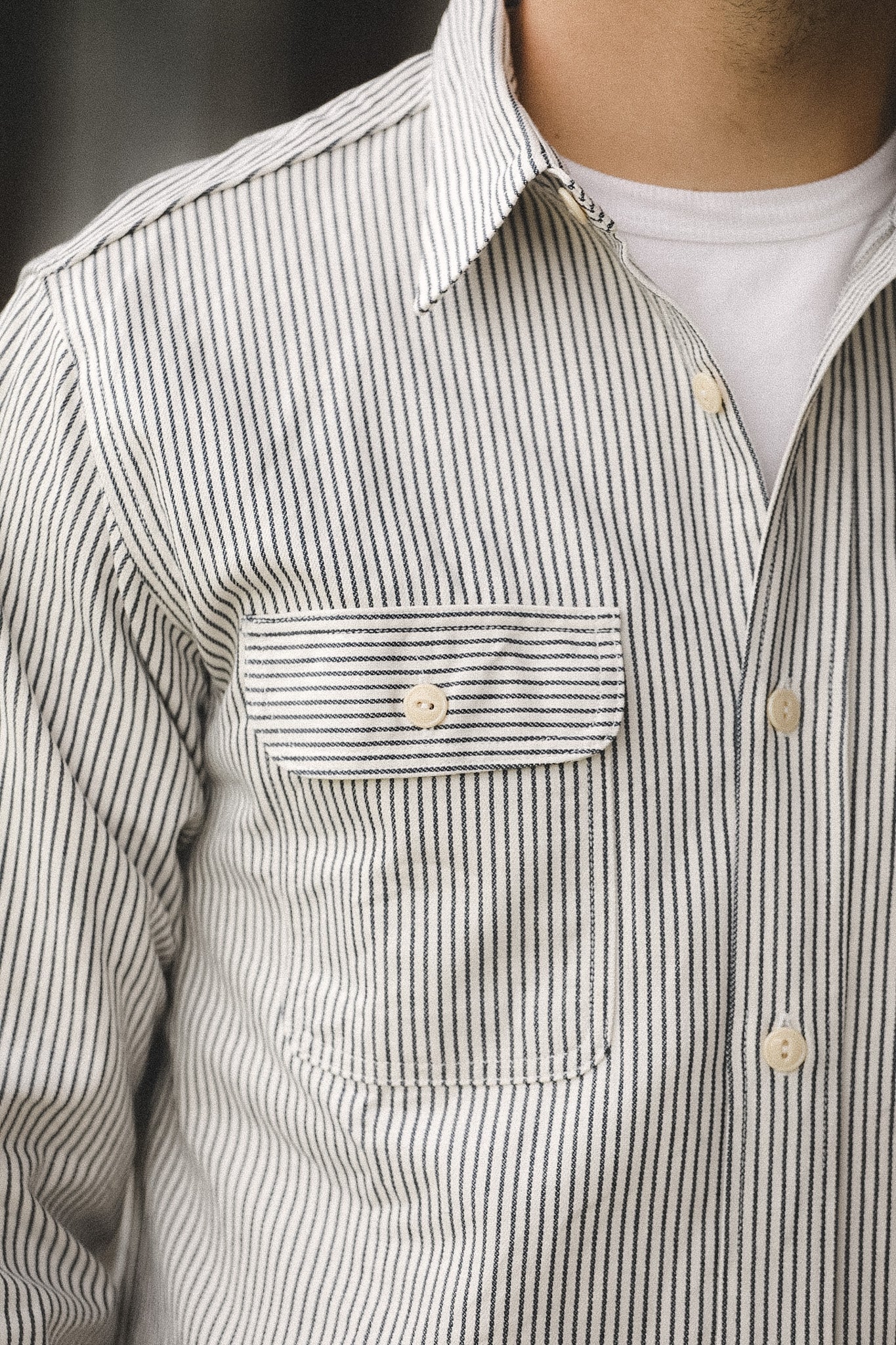 Close-up of a person wearing a striped shirt with a pocket and collar.