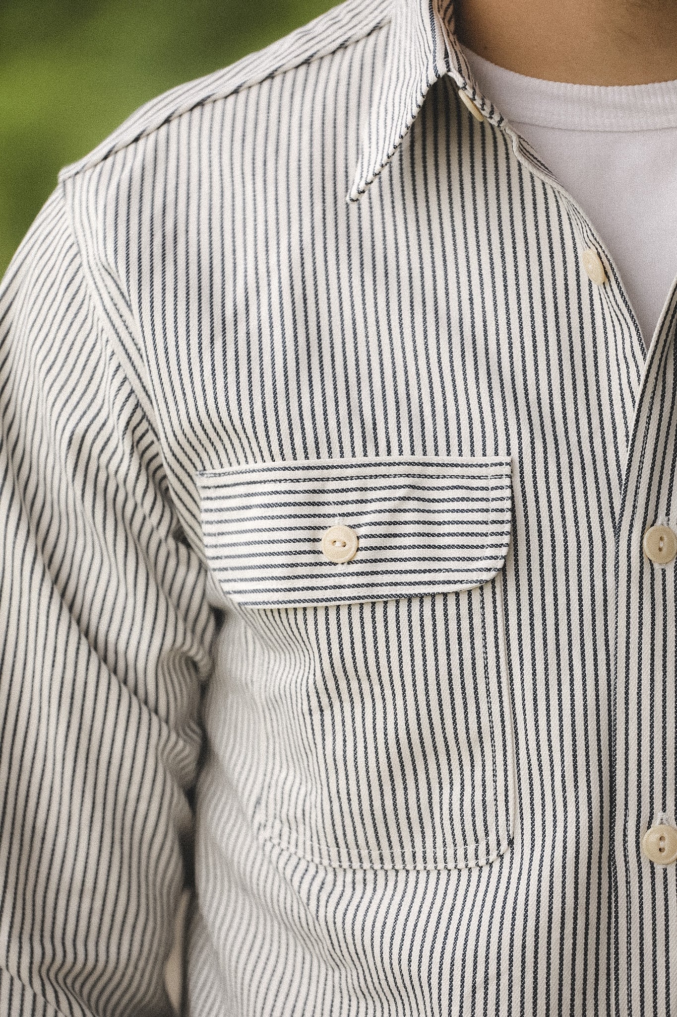 Close-up of a person wearing a striped shirt with a pocket and buttons.
