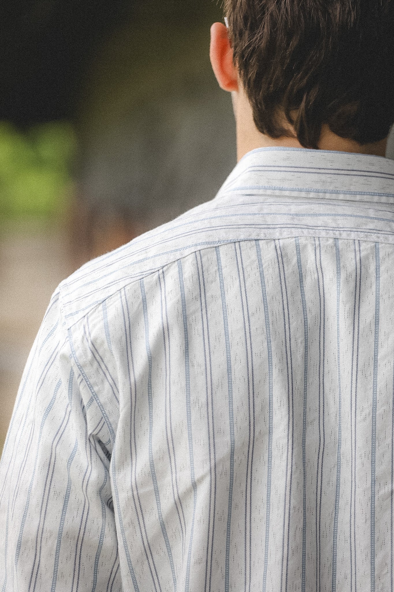 Person wearing a striped shirt with a blurred background
