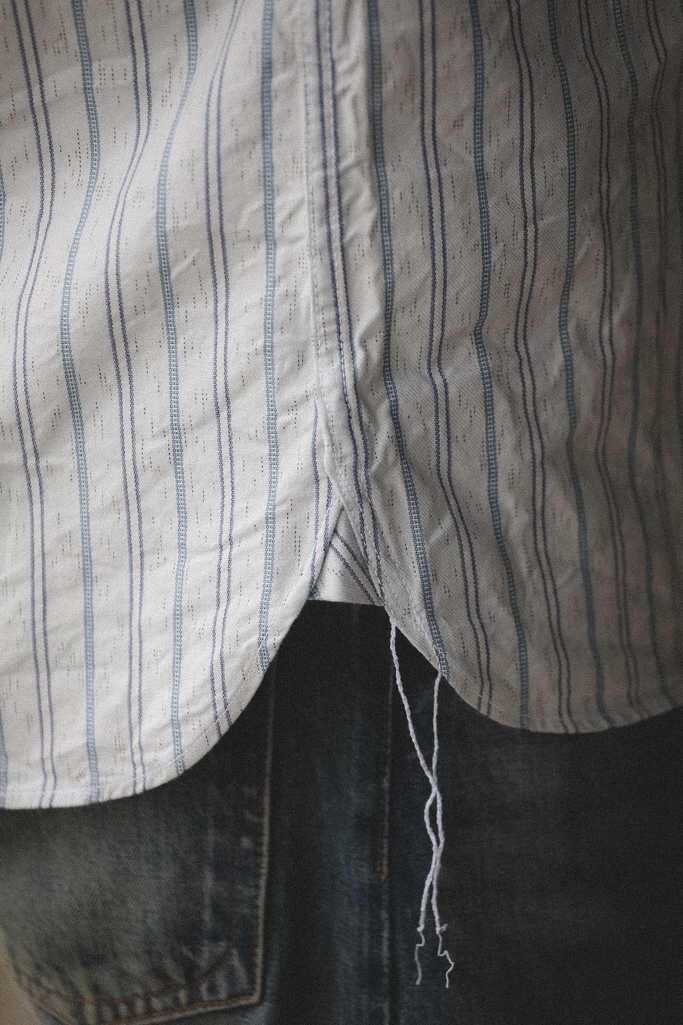 Close-up of a striped shirt with a pocket and dark pants.