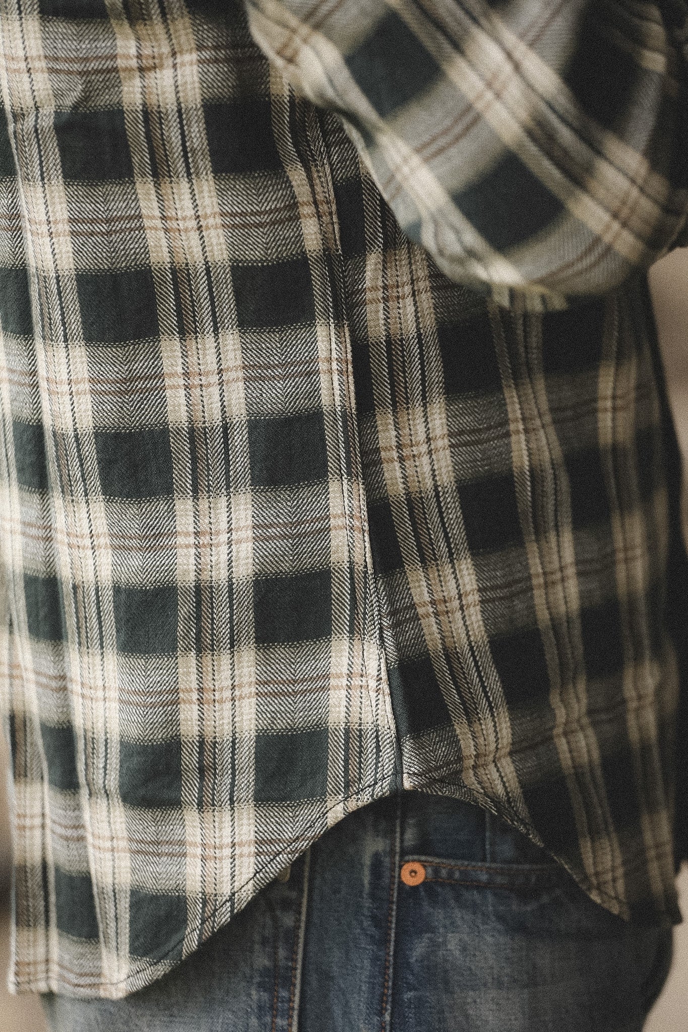 Close-up of a plaid shirt and jeans with a neutral background