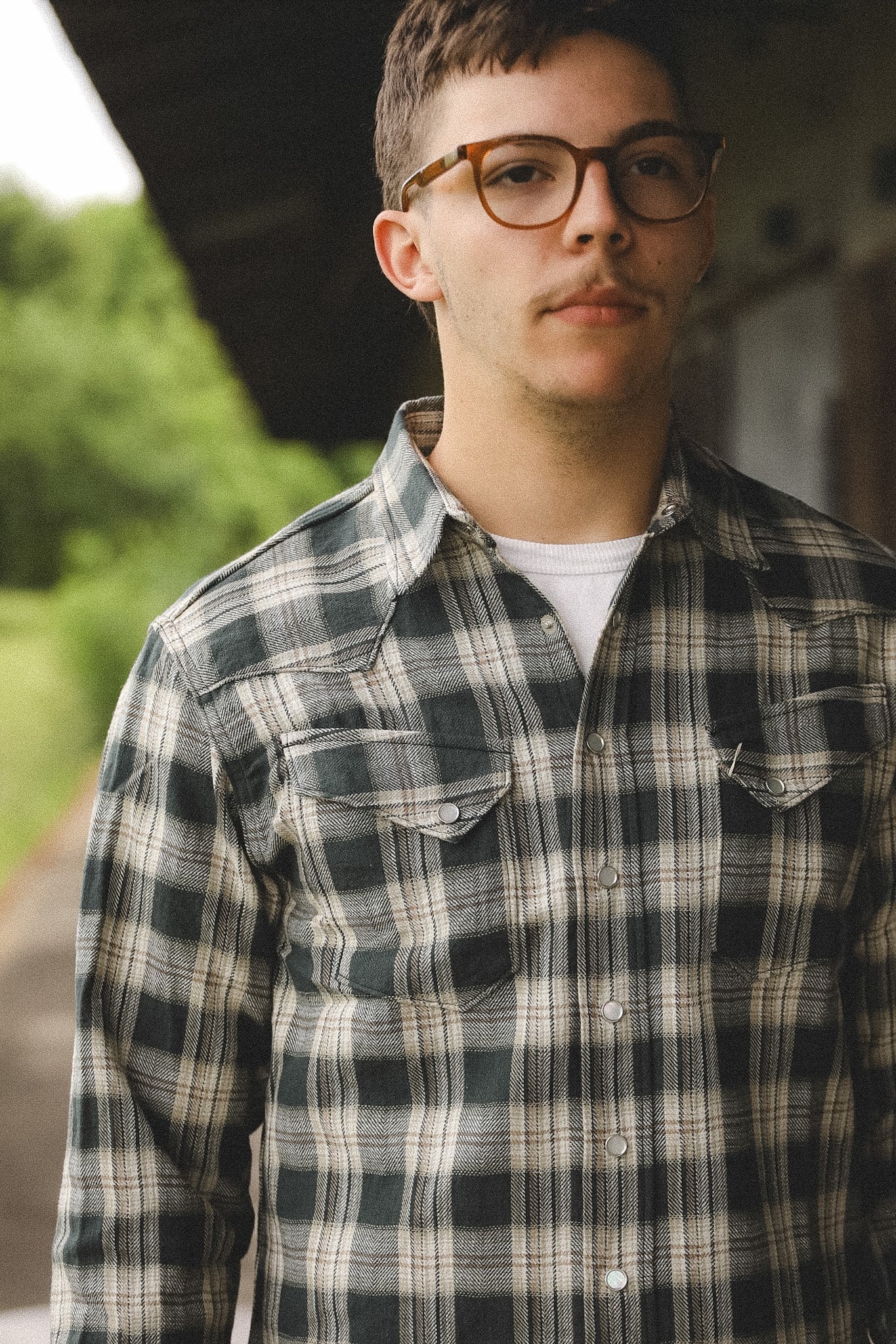 Person wearing a plaid shirt and glasses outdoors