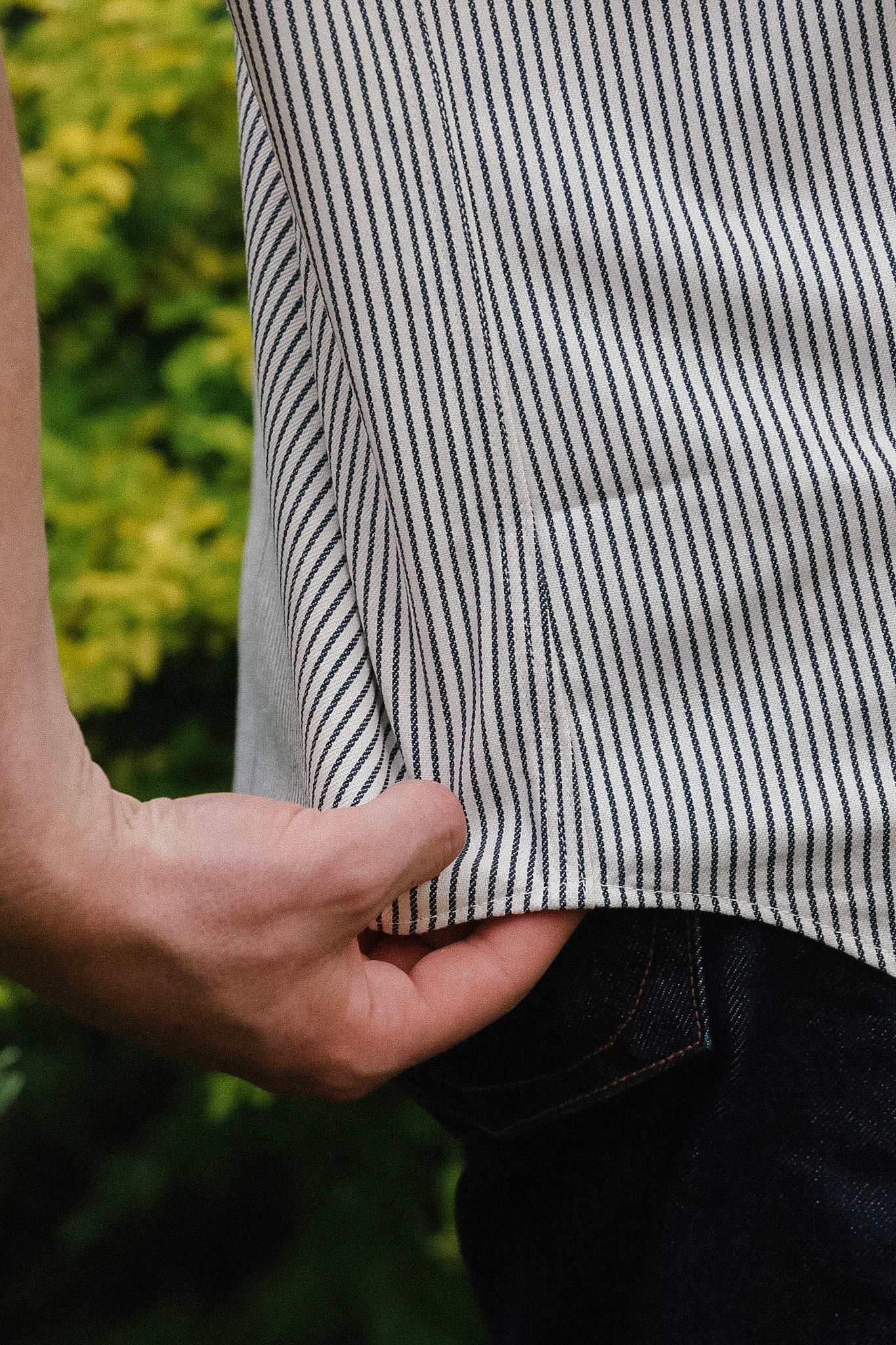 Close-up of a person wearing a black and white striped shirt with a blurred green background