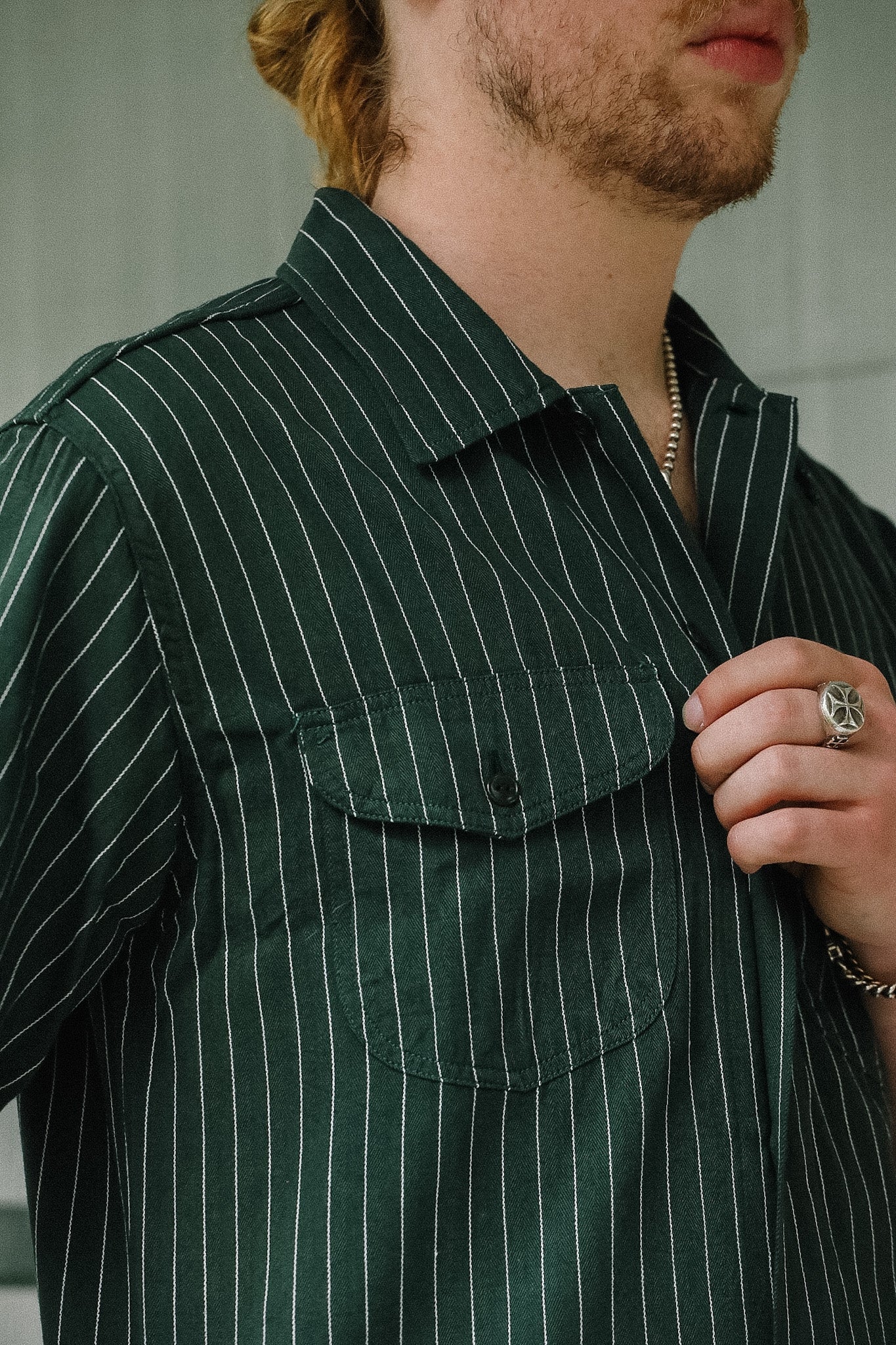 Person wearing a green pinstripe shirt with a blurred background