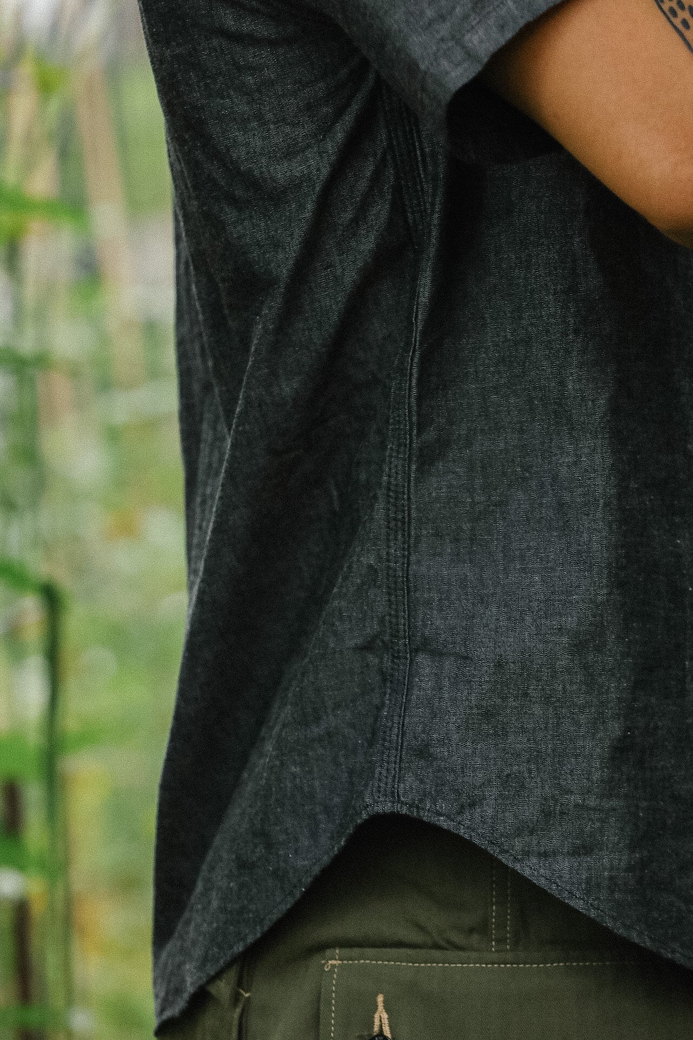 Person wearing a dark gray shirt with a blurred green background