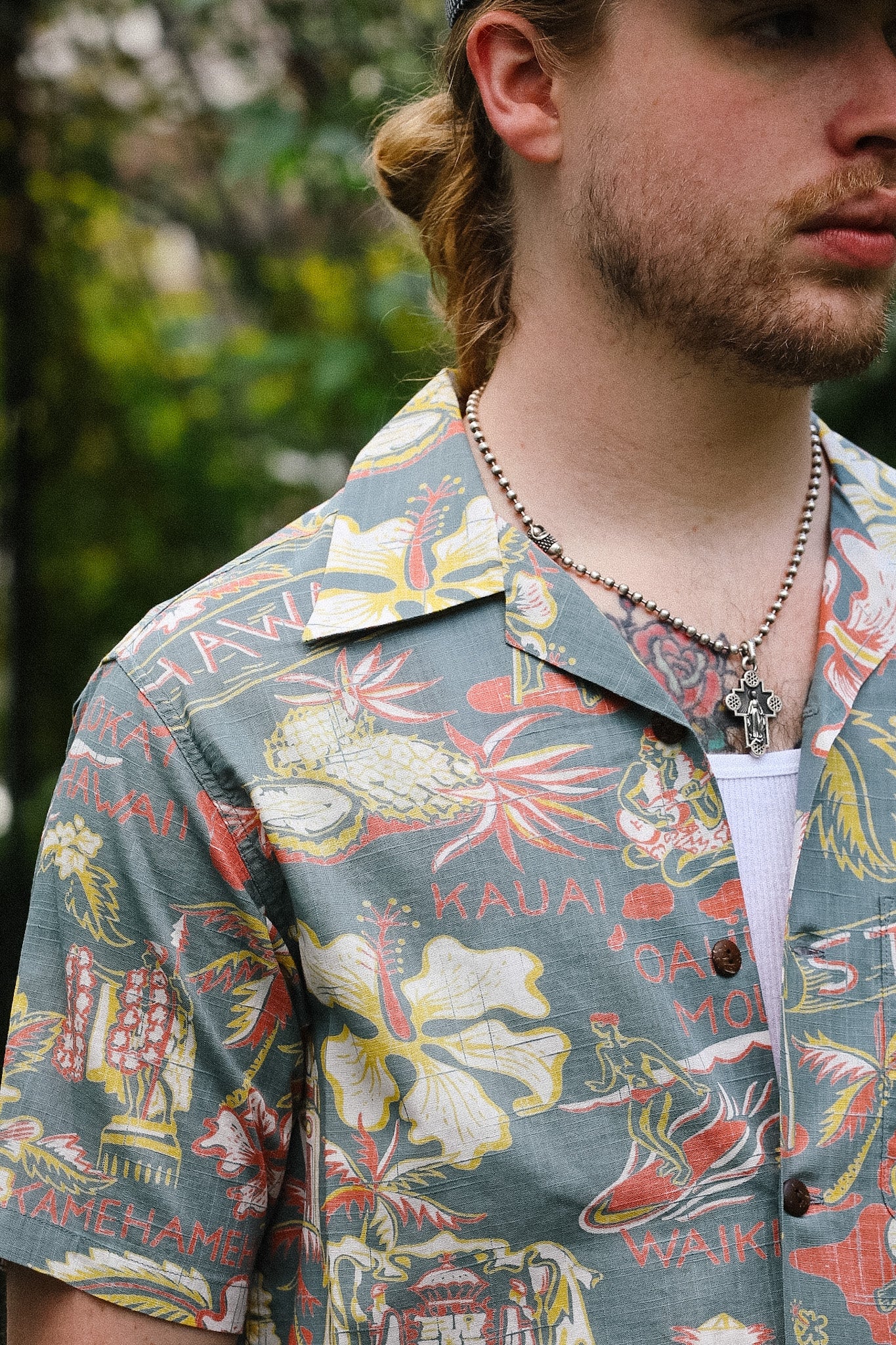 Man wearing a colorful Hawaiian shirt with floral and text patterns.