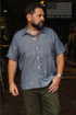 Man wearing short sleeve blue pinstripe work shirt and olive green pants with Made in the USA flag logo